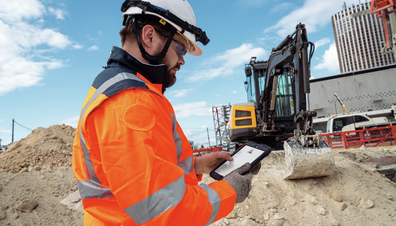 Um trabalhador num local de trabalho de construção observa o seu tablet